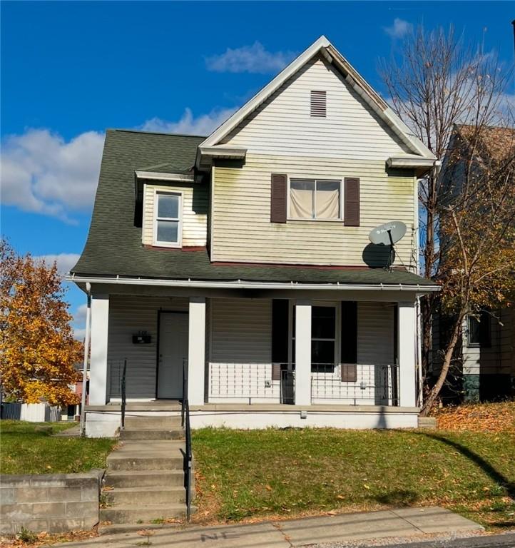 front facade with covered porch and a front yard