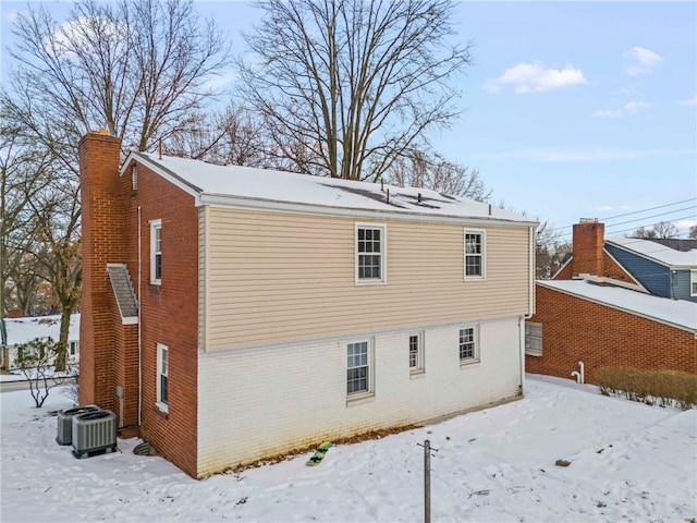 snow covered back of property featuring cooling unit