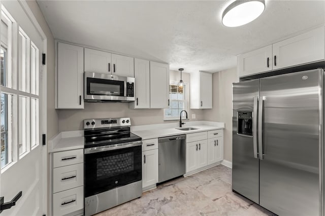 kitchen with appliances with stainless steel finishes, decorative light fixtures, sink, and white cabinets