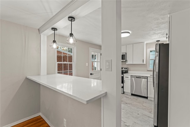 kitchen with pendant lighting, appliances with stainless steel finishes, kitchen peninsula, and white cabinets