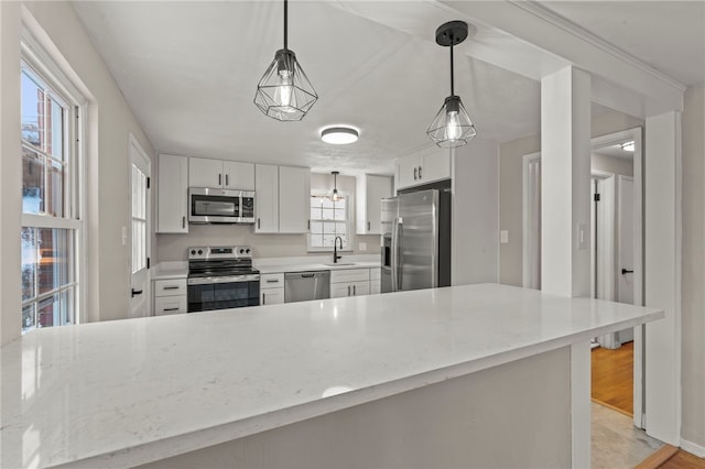 kitchen with pendant lighting, stainless steel appliances, sink, and white cabinets