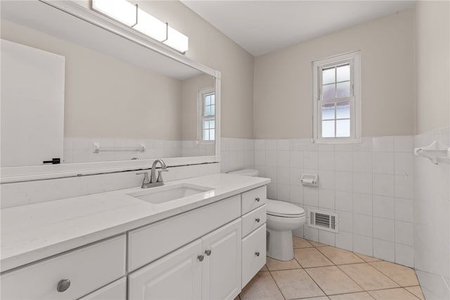 bathroom featuring tile patterned flooring, vanity, toilet, and a healthy amount of sunlight