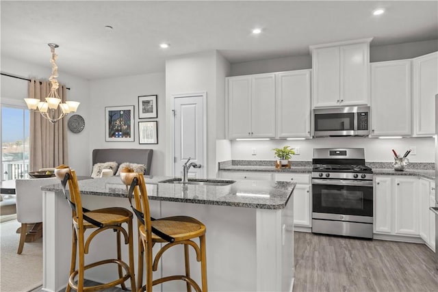 kitchen with sink, a breakfast bar area, white cabinets, a kitchen island with sink, and stainless steel appliances