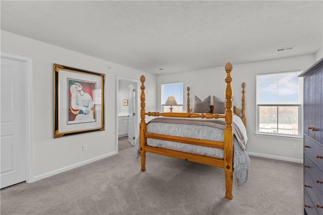 bedroom featuring ensuite bathroom and light carpet