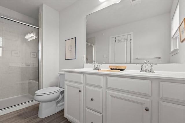 bathroom featuring vanity, wood-type flooring, a shower with door, and toilet