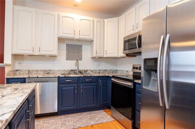 kitchen with blue cabinetry, white cabinetry, and appliances with stainless steel finishes