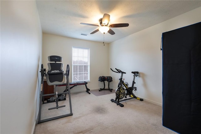 exercise area featuring light carpet, a textured ceiling, and ceiling fan