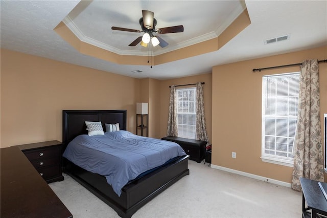 bedroom featuring light carpet, a tray ceiling, ornamental molding, and ceiling fan