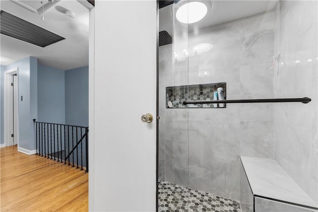 bathroom featuring wood-type flooring and a tile shower