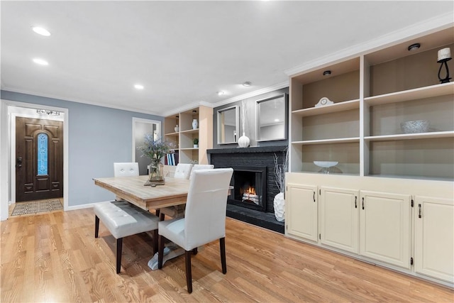 dining space featuring crown molding, a brick fireplace, and light wood-type flooring