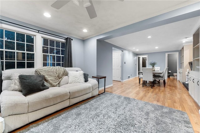 living room featuring ornamental molding, ceiling fan, and light wood-type flooring