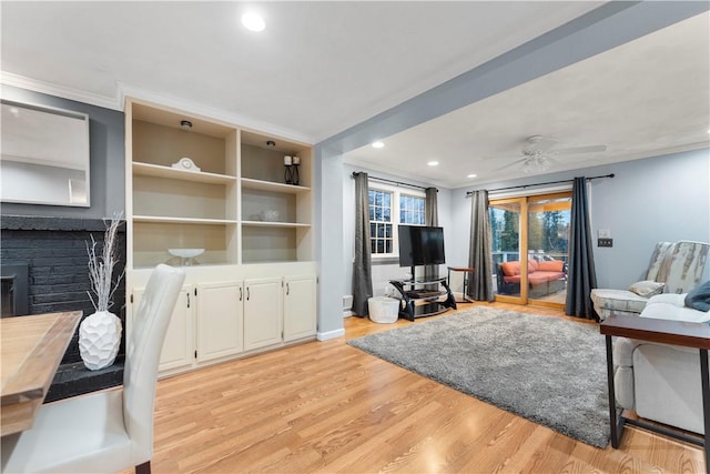 living room with crown molding, ceiling fan, light hardwood / wood-style floors, and a brick fireplace