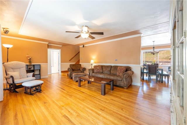 living room featuring crown molding, wood-type flooring, and ceiling fan with notable chandelier