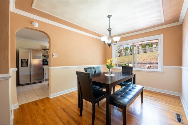 dining space featuring ornamental molding, a notable chandelier, and light wood-type flooring