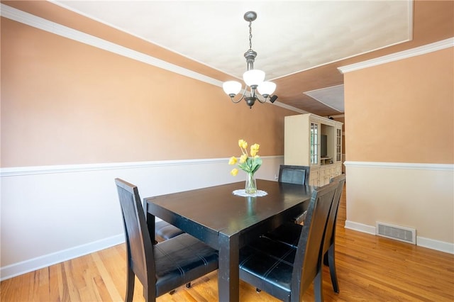 dining space featuring ornamental molding, a notable chandelier, and light wood-type flooring