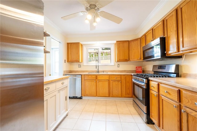 kitchen featuring sink, light tile patterned floors, ceiling fan, appliances with stainless steel finishes, and ornamental molding