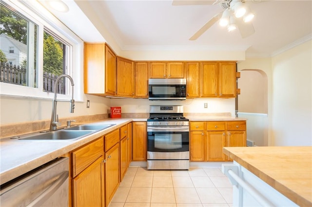 kitchen featuring sink, crown molding, light tile patterned floors, ceiling fan, and appliances with stainless steel finishes