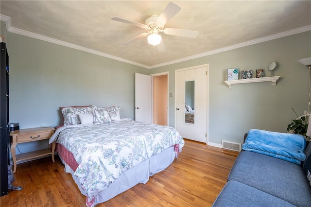 bedroom with ceiling fan, ornamental molding, and wood-type flooring