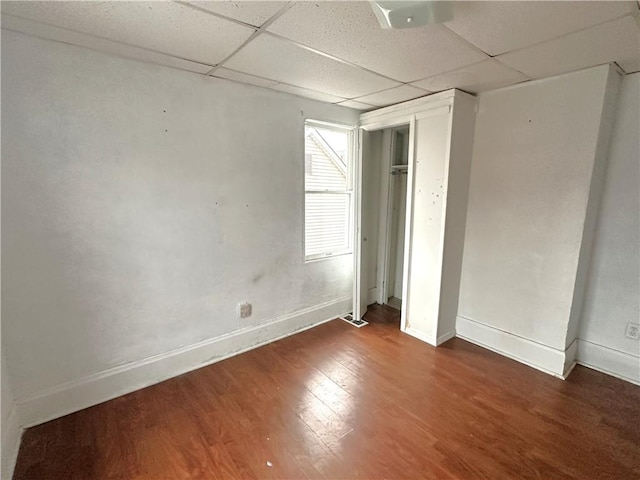 unfurnished bedroom with a paneled ceiling and dark hardwood / wood-style floors