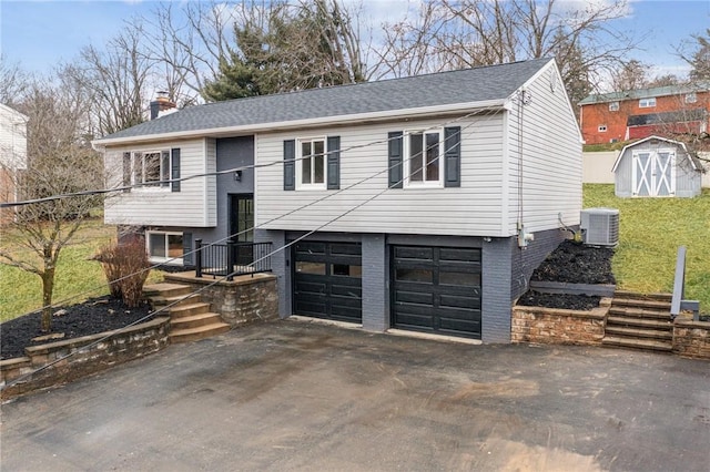 split foyer home with cooling unit, a garage, and a storage unit