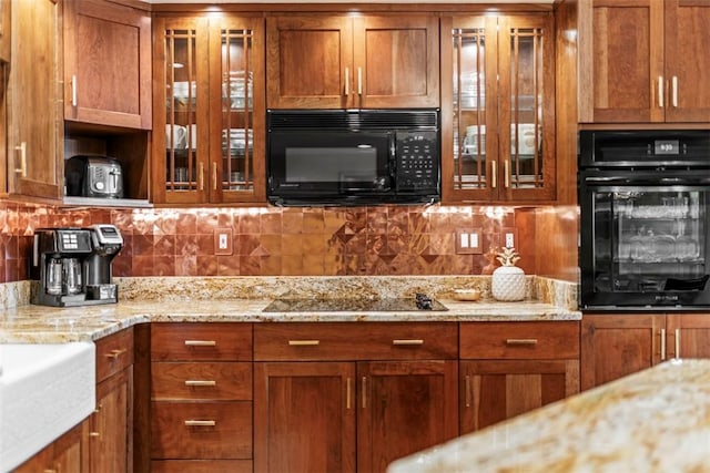 kitchen featuring black appliances, brown cabinets, and glass insert cabinets