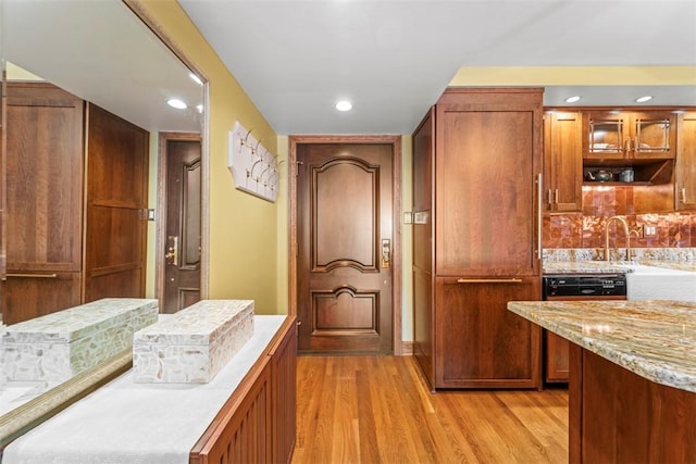 kitchen with brown cabinets, light wood-style flooring, light stone counters, tasteful backsplash, and recessed lighting