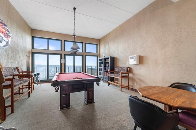 game room with healthy amount of natural light, a textured wall, pool table, carpet flooring, and a towering ceiling