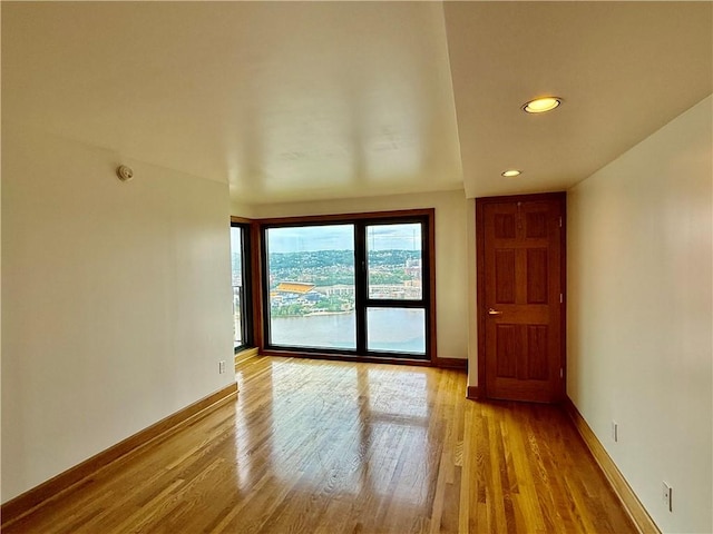 empty room featuring wood finished floors, baseboards, and recessed lighting