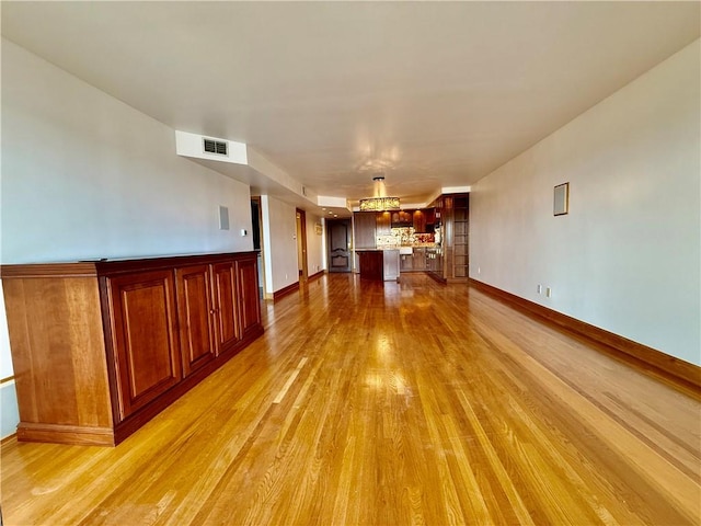 unfurnished living room featuring light wood-type flooring and baseboards