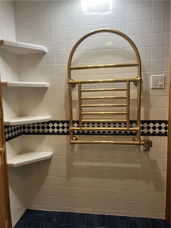 full bath featuring tiled shower, tile patterned floors, and a towel warming rack