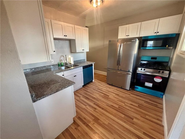 30 1st St, Leetsdale, PA 15056 - kitchen featuring stainless steel appliances, light wood-type flooring, white cabinetry, a sink, and dark stone countertops