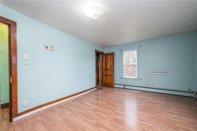 unfurnished room with baseboard heating and light wood-type flooring