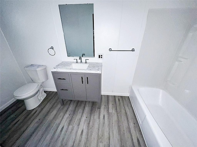 bathroom with wood-type flooring, a bath, vanity, and toilet