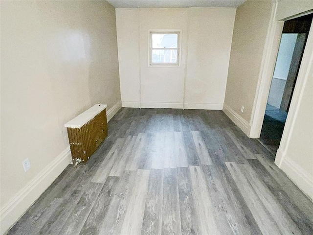 empty room with hardwood / wood-style flooring and radiator