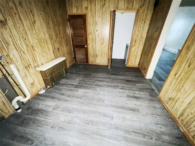 spare room with radiator heating unit, wooden walls, and dark hardwood / wood-style flooring