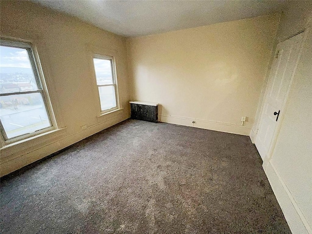 carpeted spare room with radiator and a wealth of natural light