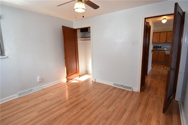 unfurnished bedroom featuring a wall mounted AC, light hardwood / wood-style floors, a closet, and ceiling fan