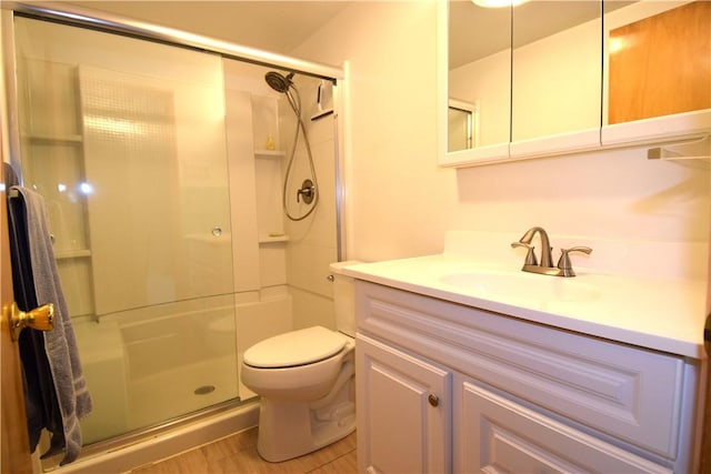 bathroom featuring vanity, a shower with door, and toilet