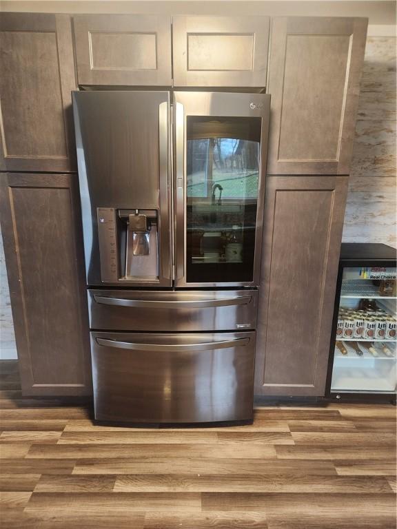 kitchen with dark brown cabinetry, stainless steel fridge, and light hardwood / wood-style flooring