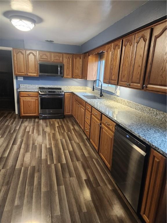 kitchen featuring sink, stainless steel appliances, dark hardwood / wood-style floors, and light stone countertops