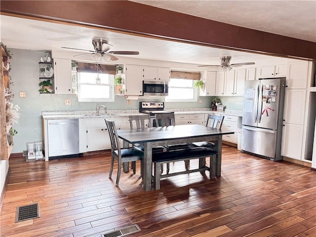 kitchen with dark wood-type flooring, stainless steel appliances, sink, and white cabinets