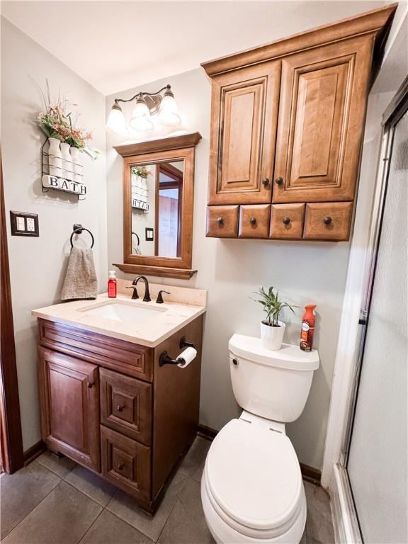 bathroom featuring vanity, an enclosed shower, tile patterned floors, and toilet