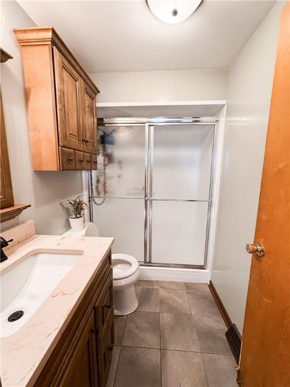 bathroom with vanity, toilet, an enclosed shower, and tile patterned flooring