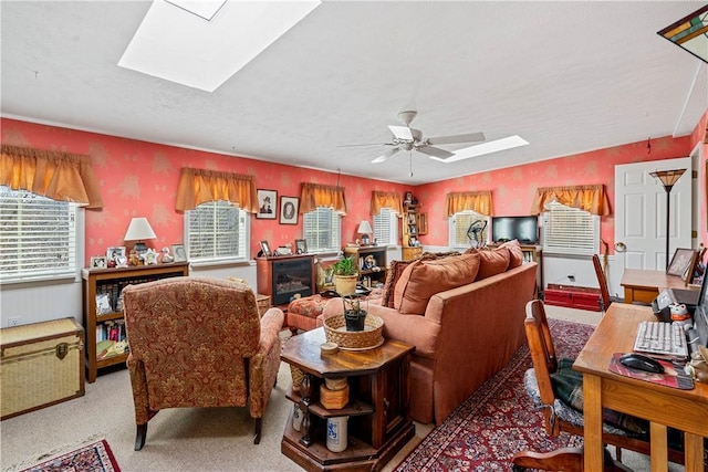 living room with ceiling fan, a skylight, and light carpet