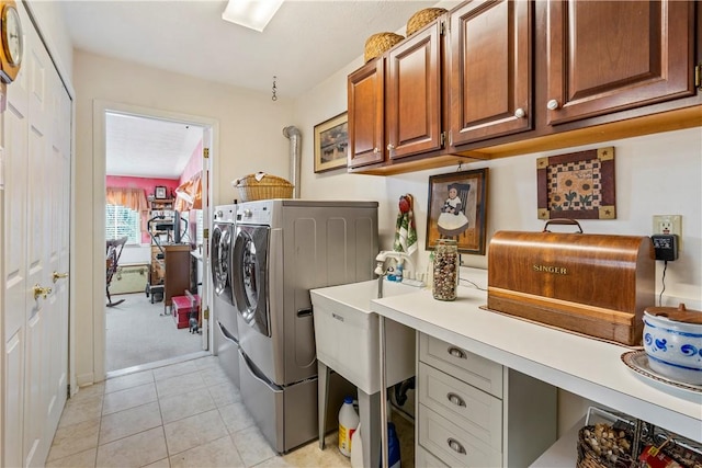 clothes washing area featuring cabinets, separate washer and dryer, and light tile patterned floors