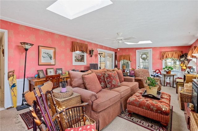 carpeted living room with ceiling fan, ornamental molding, and a skylight