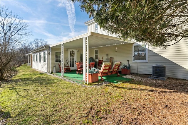 rear view of property featuring central AC unit, a lawn, and a patio