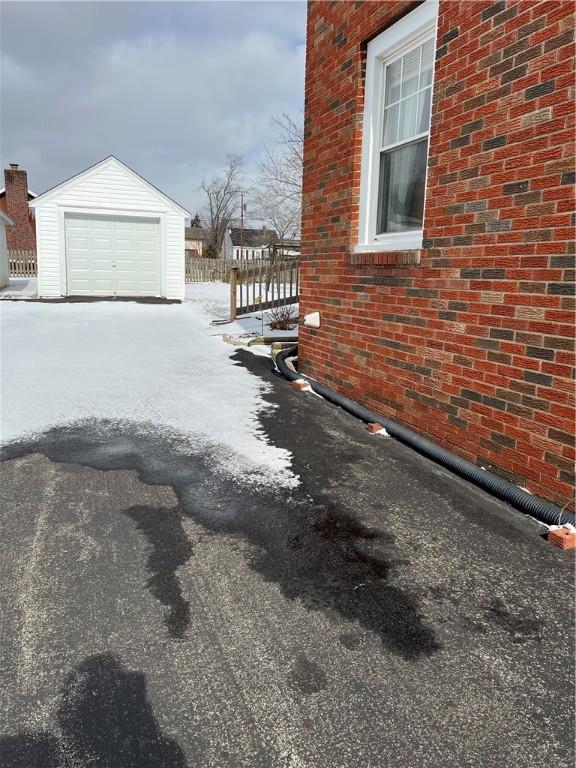 view of snowy exterior featuring a garage and an outdoor structure