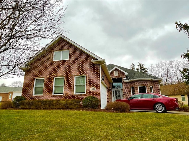 view of front of home featuring an attached garage, a front lawn, and brick siding