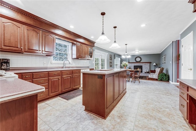 kitchen with sink, tasteful backsplash, decorative light fixtures, a center island, and ornamental molding